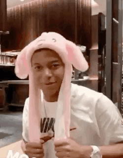 A Man Wearing A Pink Bunny Hat Is Sitting At A Table In A Restaurant . GIF