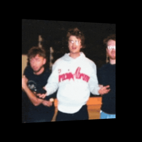 A Man Wearing A Pink Crown Sweatshirt Stands In A Group Of People GIF