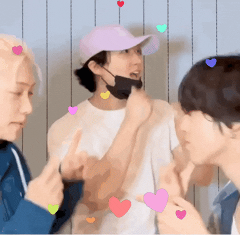 A Man Wearing A Pink Hat And A Black Mask Is Surrounded By Hearts . GIF