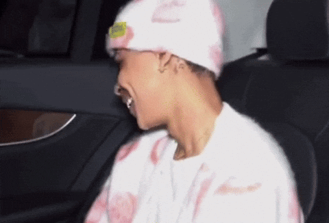 A Man Wearing A Pink Hat And A White Shirt Is Sitting In The Back Seat Of A Car GIF
