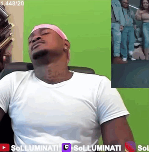 A Man Wearing A Pink Headband Sits In Front Of A Green Screen That Says Sollumini GIF