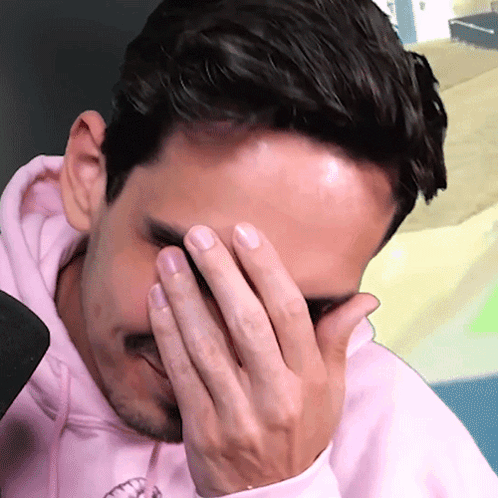 A Man Wearing A Pink Hoodie Covering His Face With His Hand GIF