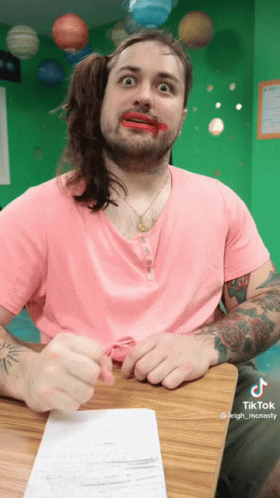 A Man Wearing A Pink Shirt Has Red Lipstick On His Lips GIF