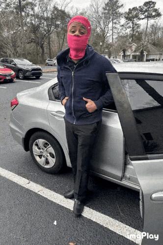 A Man Wearing A Pink Ski Mask Is Standing Next To A Car GIF
