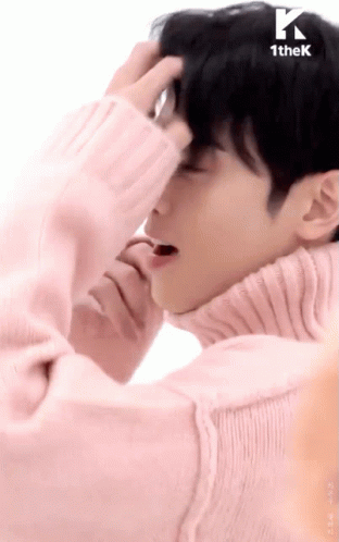 A Man Wearing A Pink Sweater Is Covering His Face With His Hand GIF