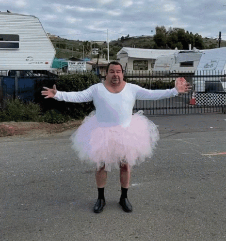 A Man Wearing A Pink Tutu Stands In Front Of A Tow Away Sign GIF