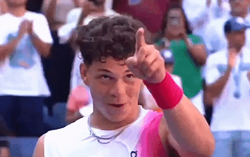 A Man Wearing A Pink Wristband Is Giving A Thumbs Up In Front Of A Crowd . GIF