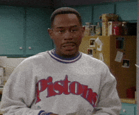 A Man Wearing A Pistons Sweatshirt Is Standing In Front Of A Refrigerator GIF