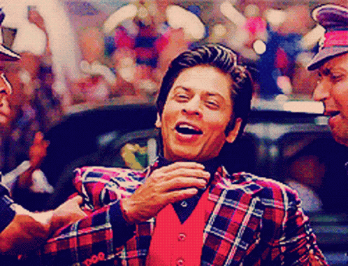 A Man Wearing A Plaid Jacket And A Red Vest Laughs GIF
