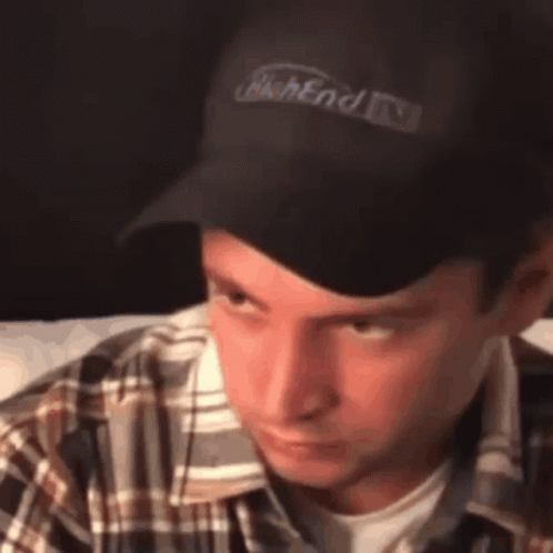 A Man Wearing A Plaid Shirt And A Black Hat With The Word Weekend Written On It GIF