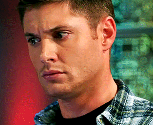 A Man Wearing A Plaid Shirt And A Black Shirt Looks At The Camera GIF