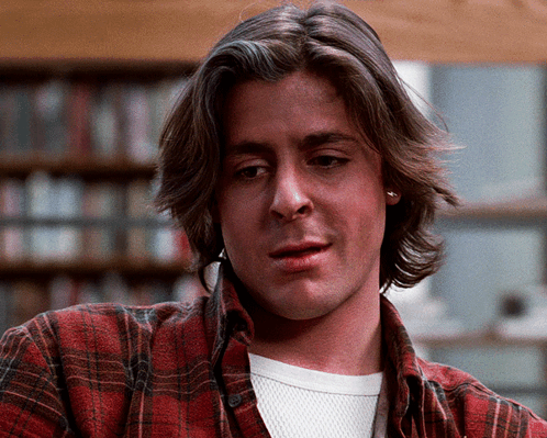 A Man Wearing A Plaid Shirt And A White Shirt Looks At The Camera GIF