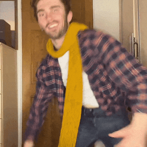A Man Wearing A Plaid Shirt And A Yellow Scarf Dancing GIF