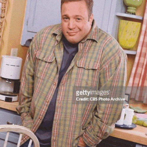 A Man Wearing A Plaid Shirt Is Standing In A Kitchen GIF