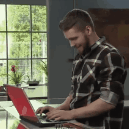 A Man Wearing A Plaid Shirt Is Typing On A Laptop GIF