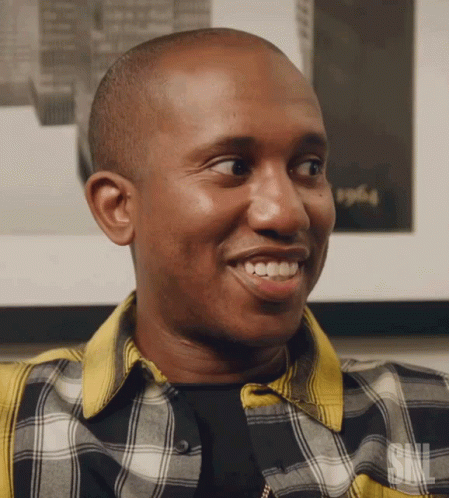 A Man Wearing A Plaid Shirt With The Letters Snl On The Bottom GIF