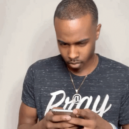 A Man Wearing A Pony T-Shirt Looks At His Cell Phone GIF