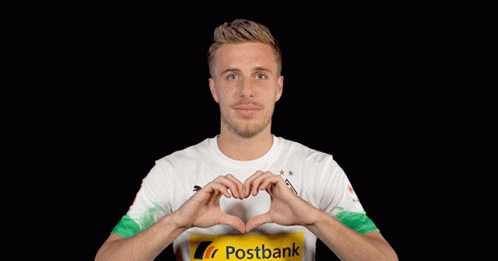 a man wearing a postbank shirt making a heart shape with his hands