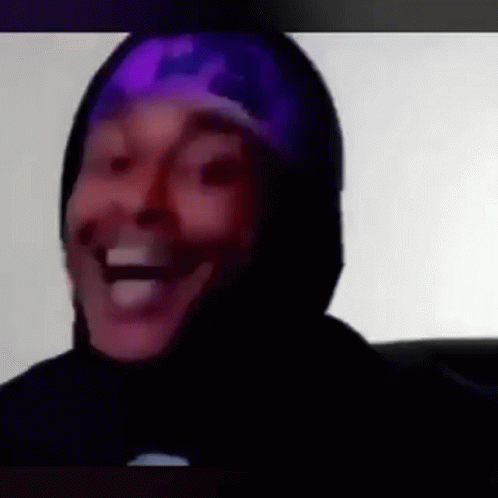 a man wearing a purple hat and a black hoodie is laughing .