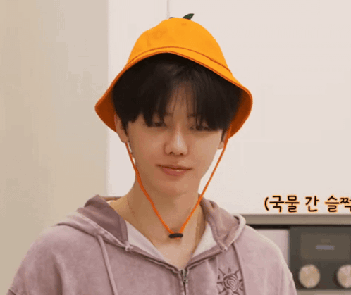 a man wearing a purple hoodie and an orange hat with a green leaf on it