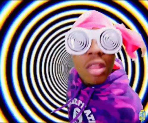 A Man Wearing A Purple Hoodie And White Glasses Is Standing In Front Of A Spiral . GIF