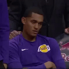 A Man Wearing A Purple Lakers Shirt Is Sitting In The Stands GIF