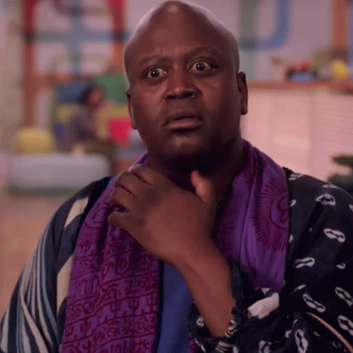 A Man Wearing A Purple Scarf Around His Neck Looks Surprised GIF
