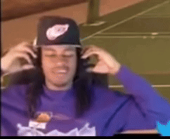A Man Wearing A Purple Shirt And A Nike Hat Is Adjusting His Headphones . GIF