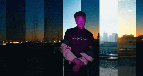 A Man Wearing A Purple Shirt That Says Anderson Stands In Front Of A City Skyline GIF