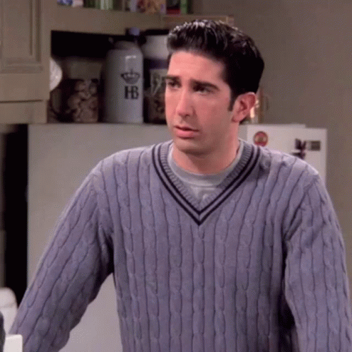A Man Wearing A Purple Sweater Is Standing In A Kitchen . GIF