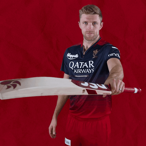 a man wearing a qatar airways jersey holds a bat