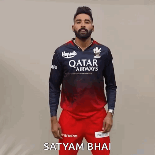 A Man Wearing A Qatar Airways Shirt And Red Pants Is Standing In Front Of A Wall . GIF