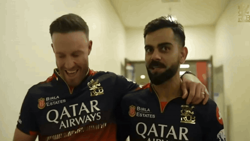A Man Wearing A Qatar Airways Shirt Stands Next To Another Man GIF