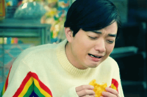 a man wearing a rainbow striped sweater is eating a waffle