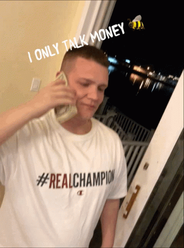 A Man Wearing A #Real Champion Shirt Is Talking On A Phone GIF