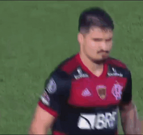 A Man Wearing A Red And Black Jersey With The Word Brb On It Is Standing On A Field . GIF