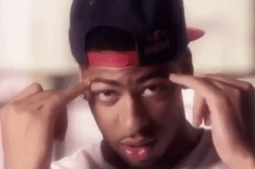 A Man Wearing A Red Bull Hat Is Holding His Hands To His Forehead . GIF