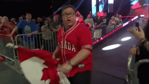 A Man Wearing A Red Canada Jersey Is Holding A Canadian Flag GIF