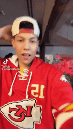 A Man Wearing A Red Chiefs Jersey And A White Hat Is Taking A Selfie . GIF