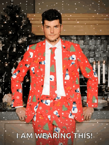 A Man Wearing A Red Christmas Suit With Snowmen And Trees On It GIF