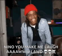 A Man Wearing A Red Hat And A Denim Jacket Is Laughing In A Dark Room . GIF