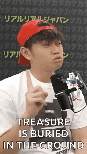 a man wearing a red hat and a white shirt is talking into a microphone while holding a toy robot .