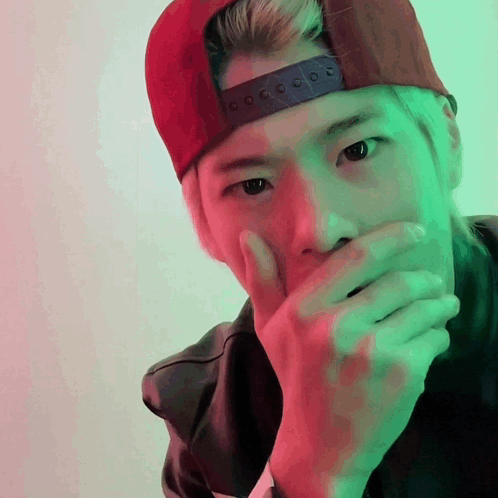 A Man Wearing A Red Hat Covering His Mouth GIF