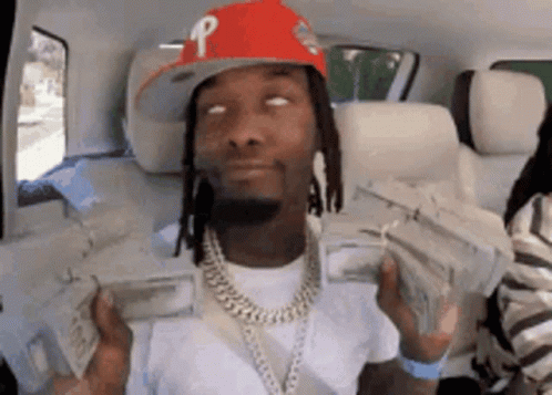 a man wearing a red hat is holding a bunch of money in his hands .