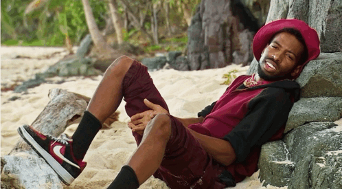 A Man Wearing A Red Hat Is Laying On A Rock GIF