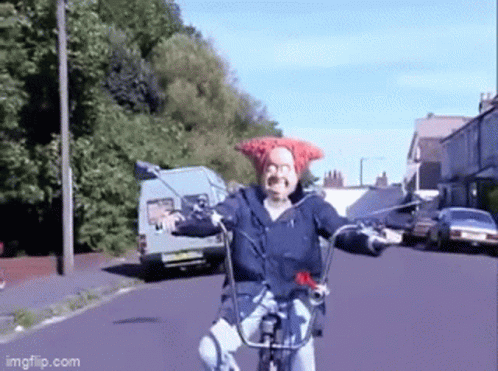 A Man Wearing A Red Hat Is Riding A Bike On A Street GIF