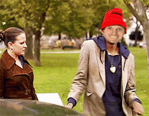 A Man Wearing A Red Hat Is Smiling While Standing Next To A Woman GIF