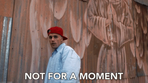 A Man Wearing A Red Hat Stands In Front Of A Wall With The Words Not For A Moment Written Below Him GIF