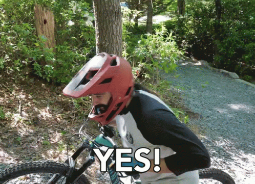 A Man Wearing A Red Helmet Is Riding A Bike And Says " Yes " In White Letters GIF