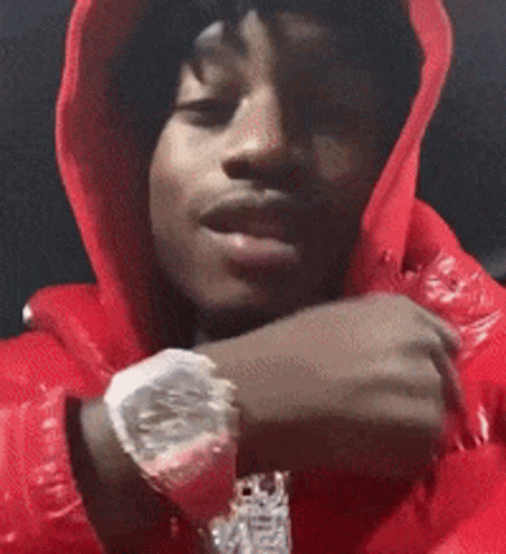 A Man Wearing A Red Hoodie And A Watch Is Looking At The Camera . GIF